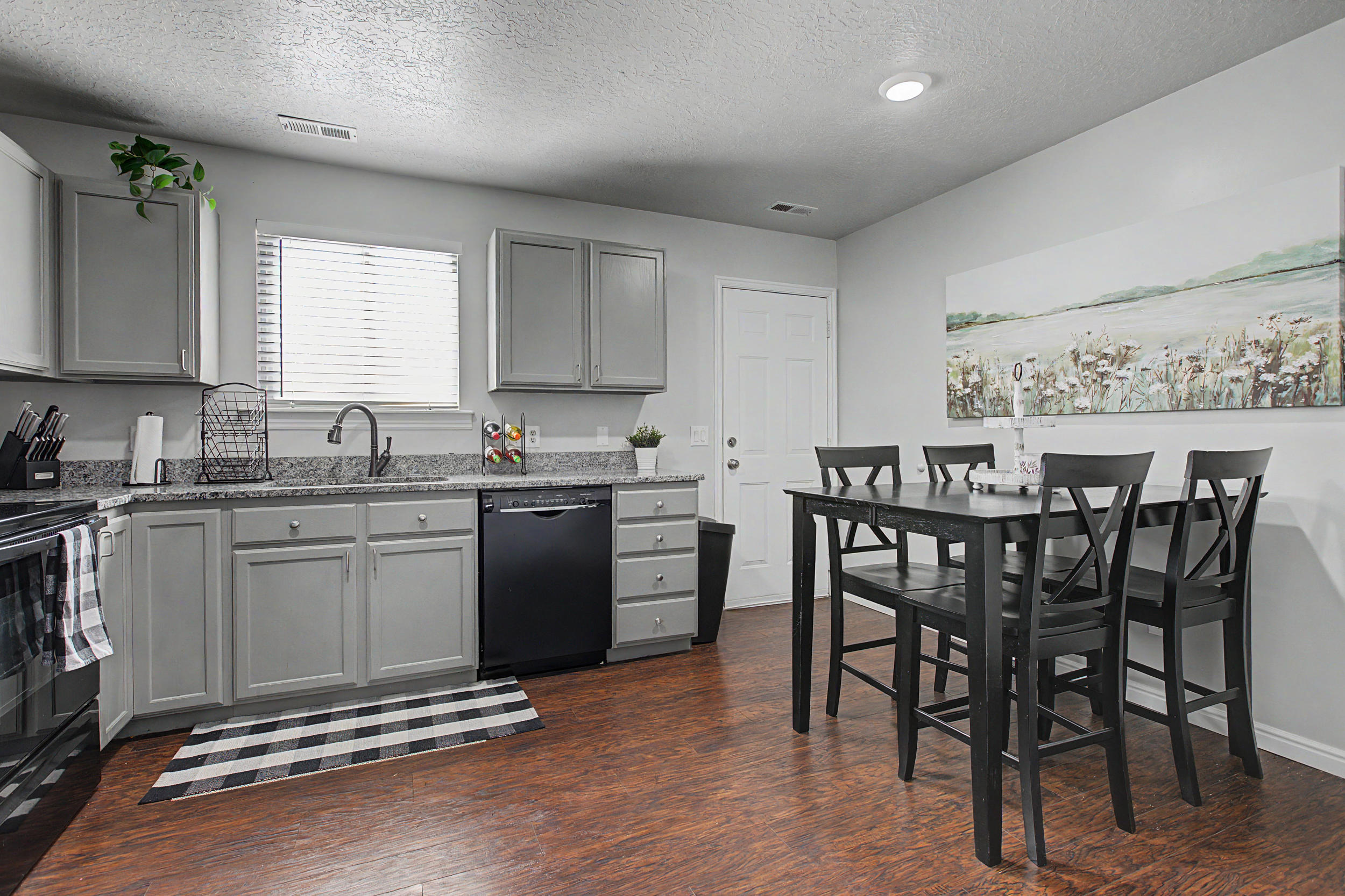 Kitchen featuring light gray cabinetry, speckled countertops, a dark finish sink faucet, and wood-finish flooring