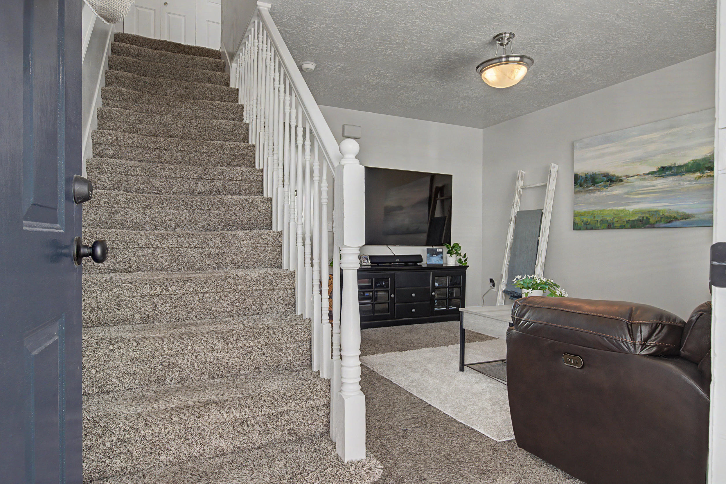 Entryway featuring a carpeted staircase with white balusters