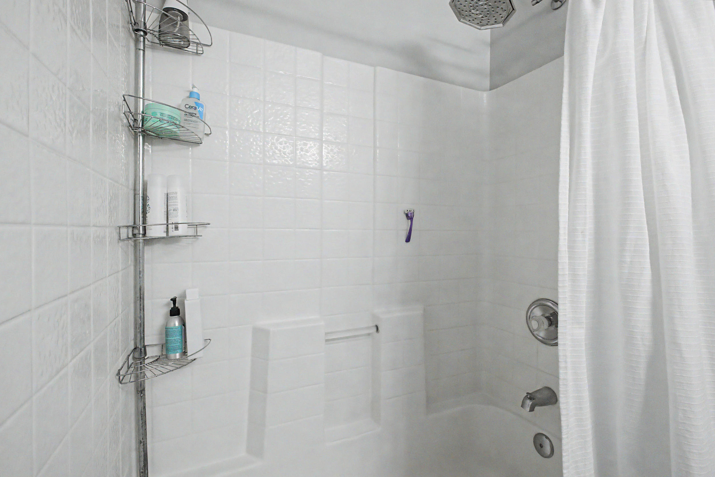 Bathtub with white tile surround and a chrome shower fixture