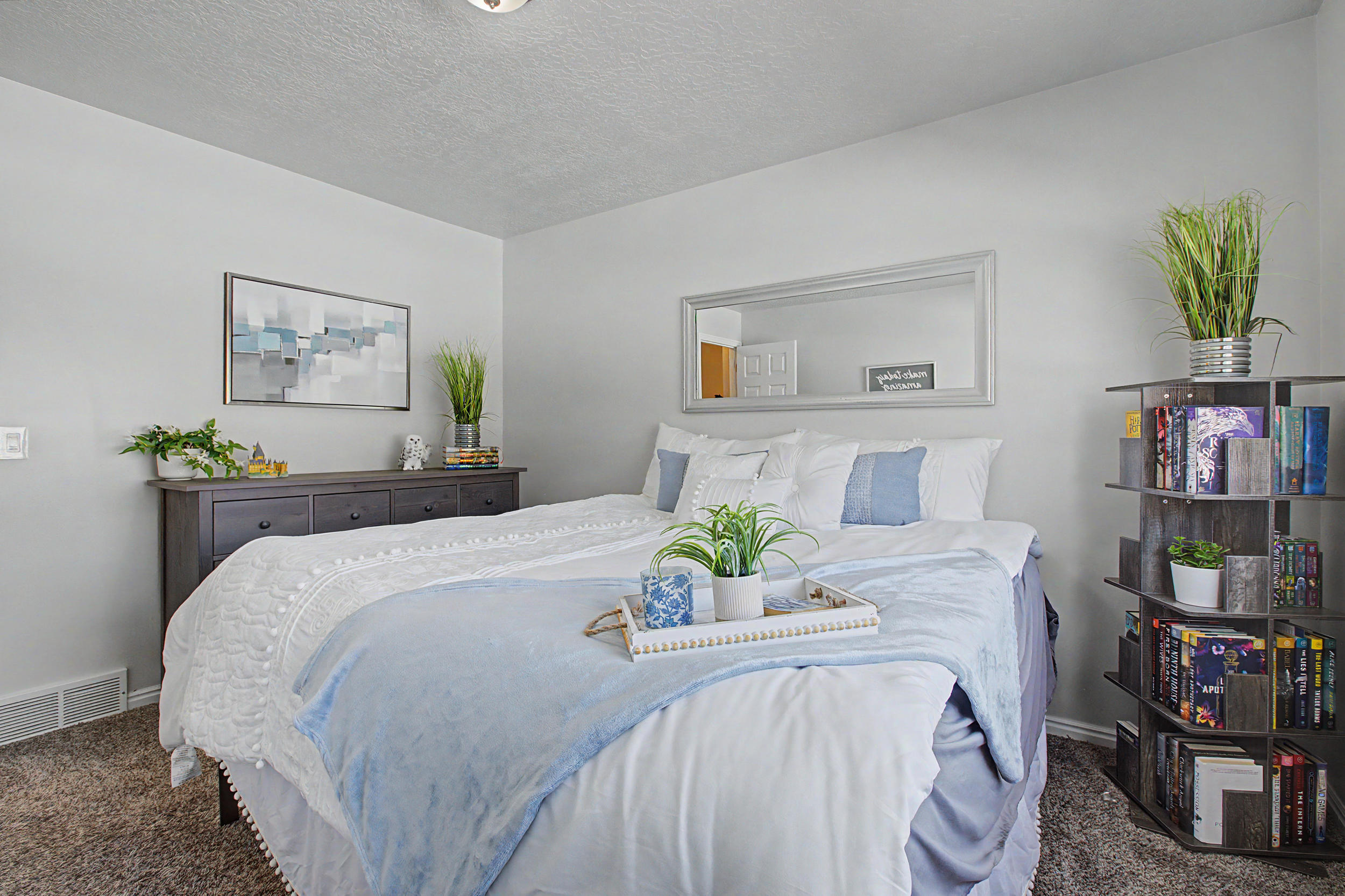 Carpeted bedroom featuring light gray walls, a built-in ceiling light, and a horizontal wall mirror