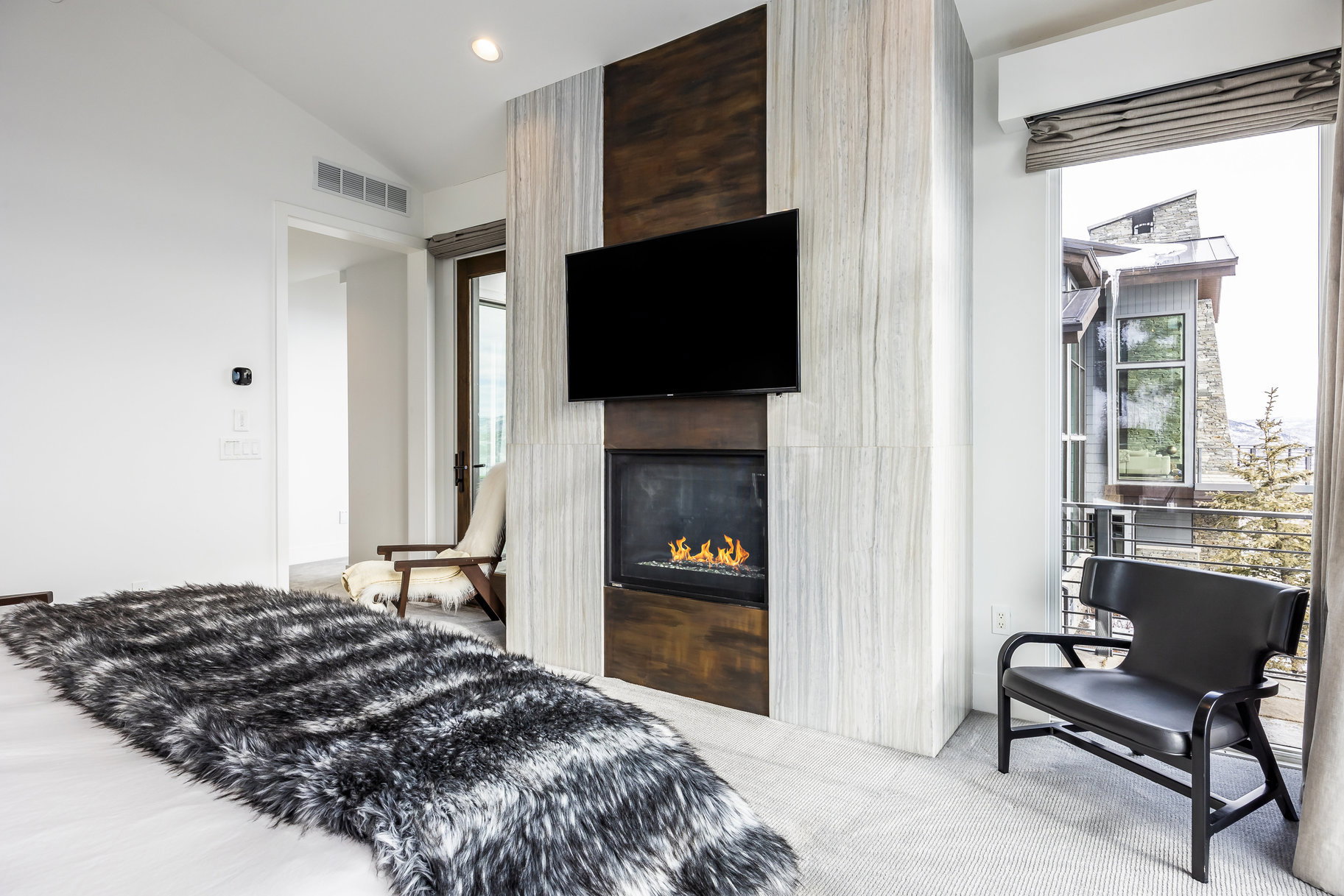 Built-in fireplace with a dark metal surround, integrated into a floor-to-ceiling accent wall featuring vertical wood paneling and stone-look tiling