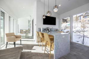 Spacious open-concept area featuring a kitchen island with stone countertop, integrated sink, and modern pendant lighting