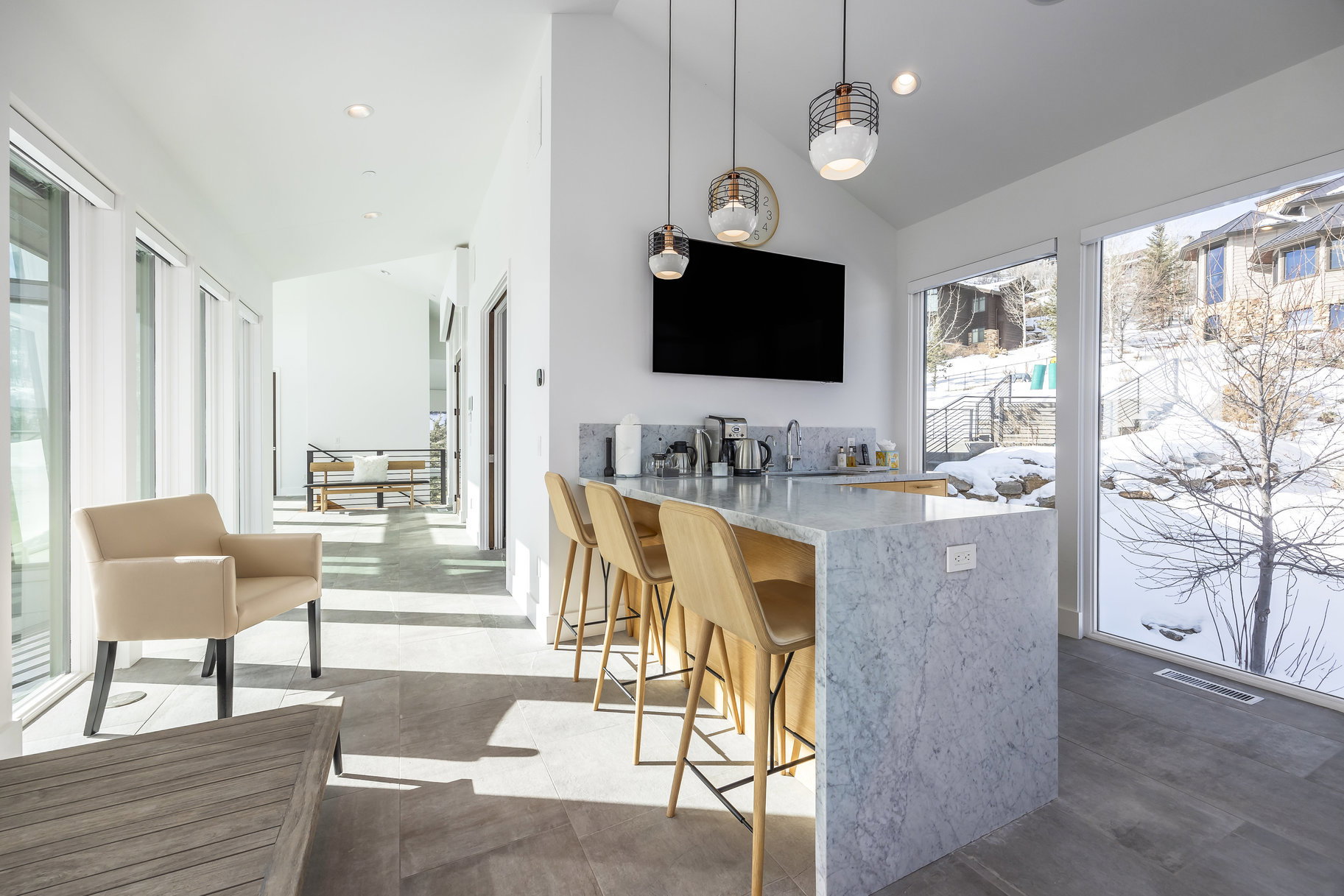 Modern wet bar featuring a quartz waterfall countertop, integrated sink, and sleek pendant lighting