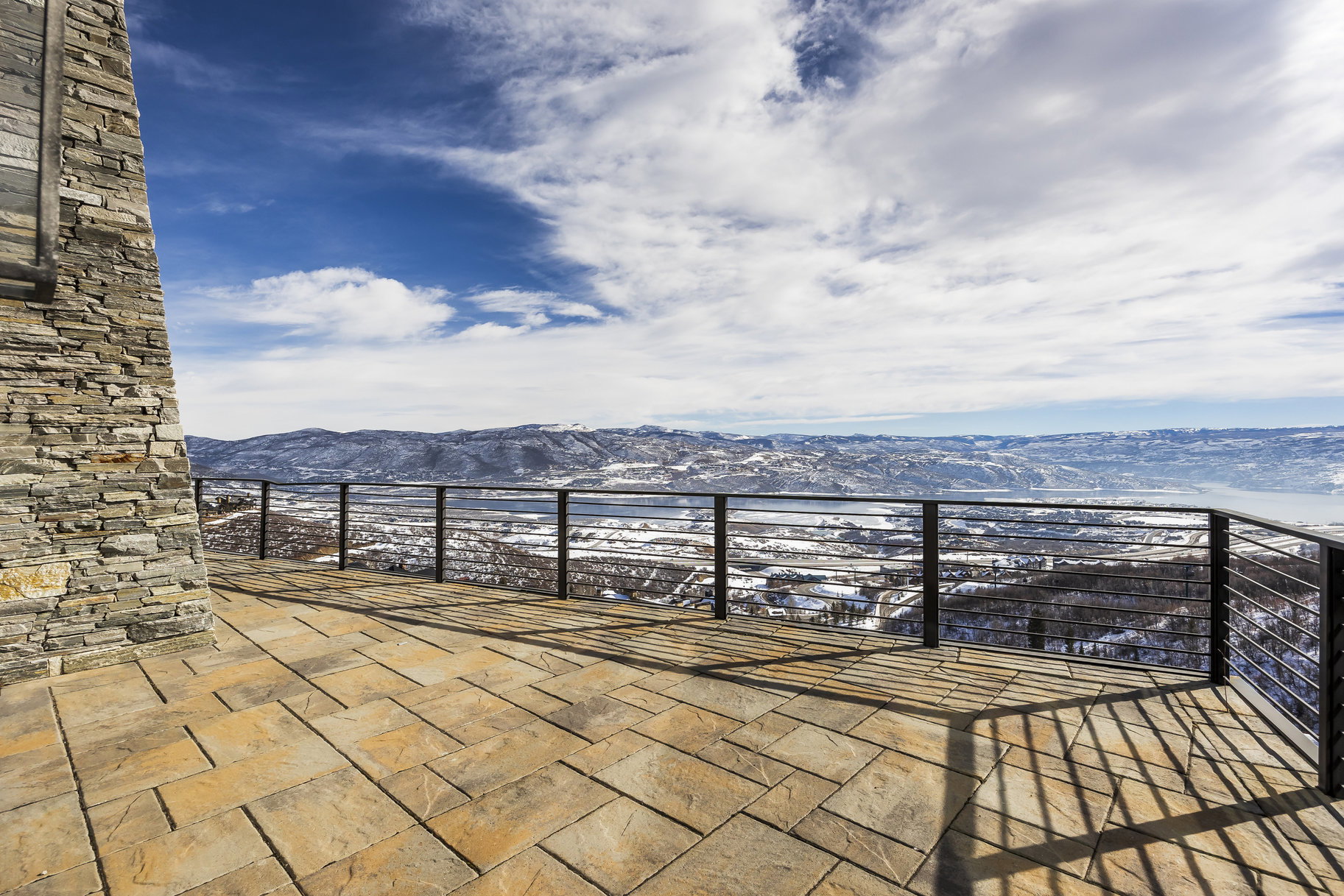 Expansive outdoor patio featuring flagstone paving and a stone-clad exterior wall