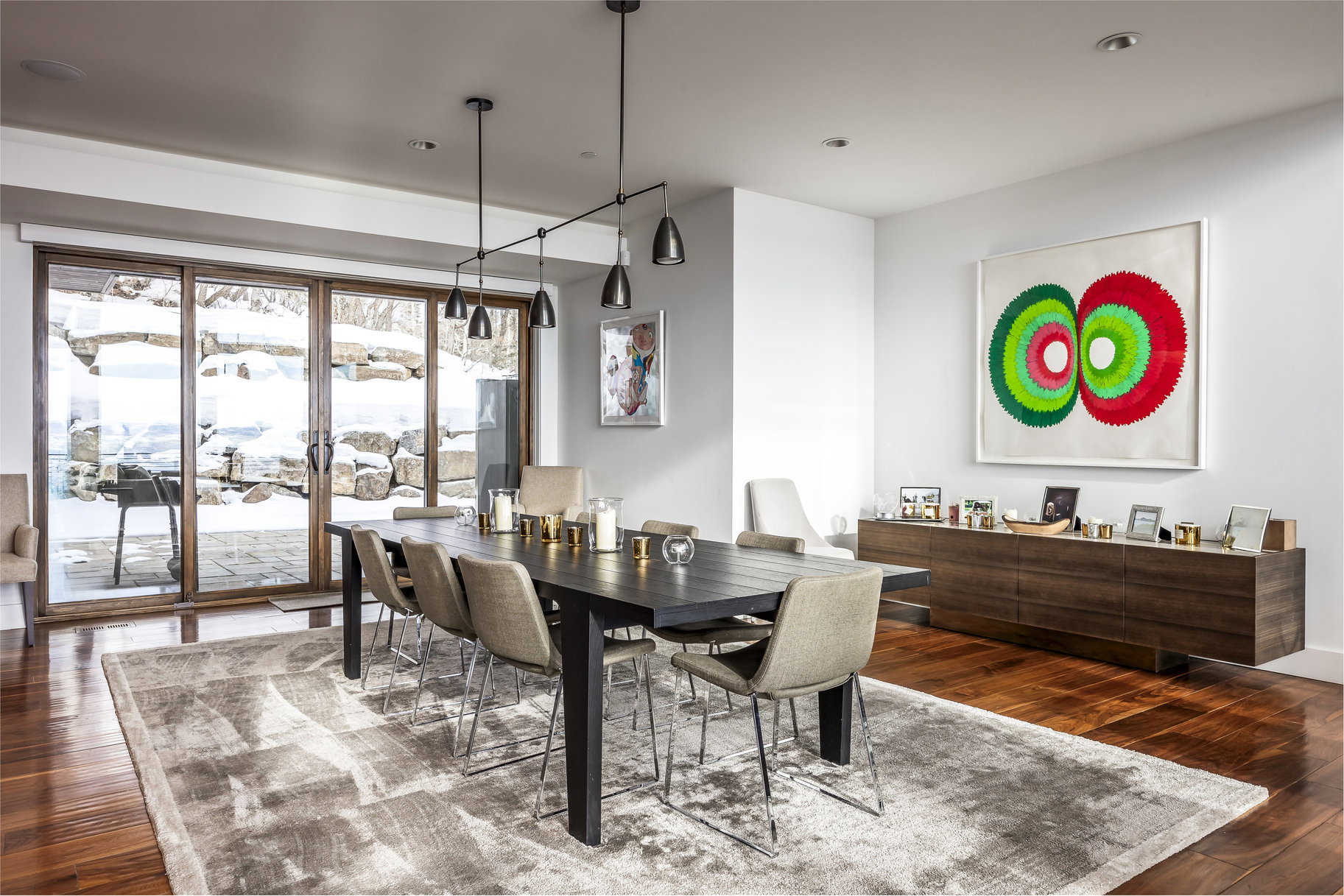 Spacious room featuring wood-finish flooring, a contemporary linear chandelier, and wide glass sliding doors