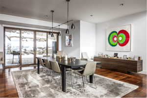 Spacious room featuring wood-finish flooring, a contemporary linear chandelier, and wide glass sliding doors