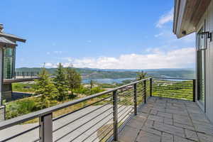 Outdoor patio featuring stone tile flooring, modern metal railing, and expansive water and mountain scenery