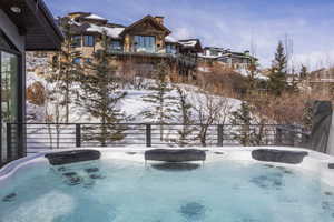 Outdoor spa tub with integrated headrests and a surrounding snow-covered landscape