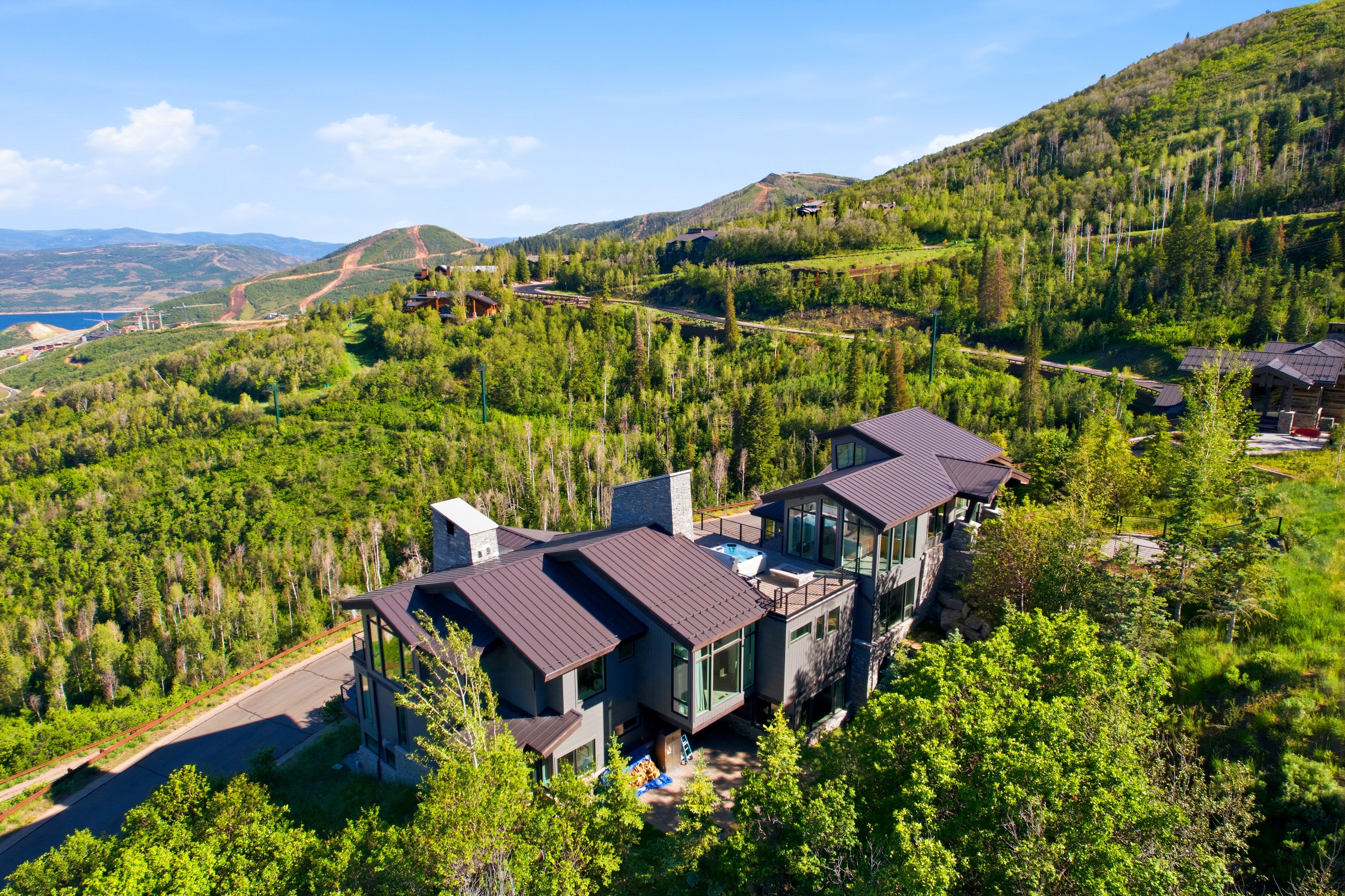 Modern mountain residence featuring multiple levels, expansive window walls, and a private deck with a built-in spa