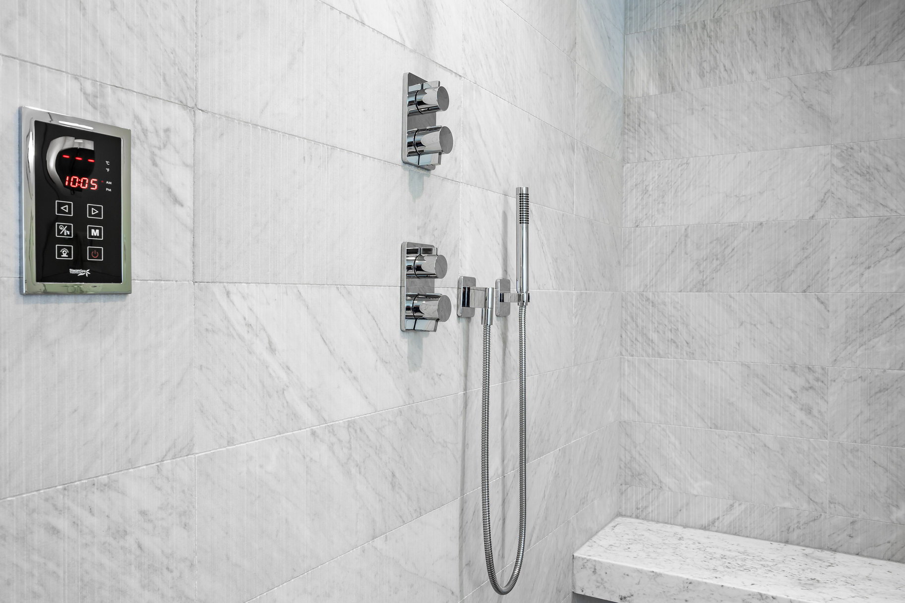 Shower featuring large format white marble-finish wall tiles, chrome fixtures, and a built-in bench