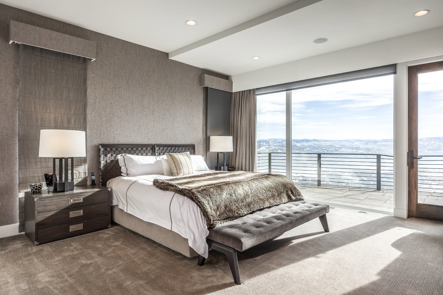 Room with floor-to-ceiling windows and sliding glass door opening to an outdoor patio with a metal railing