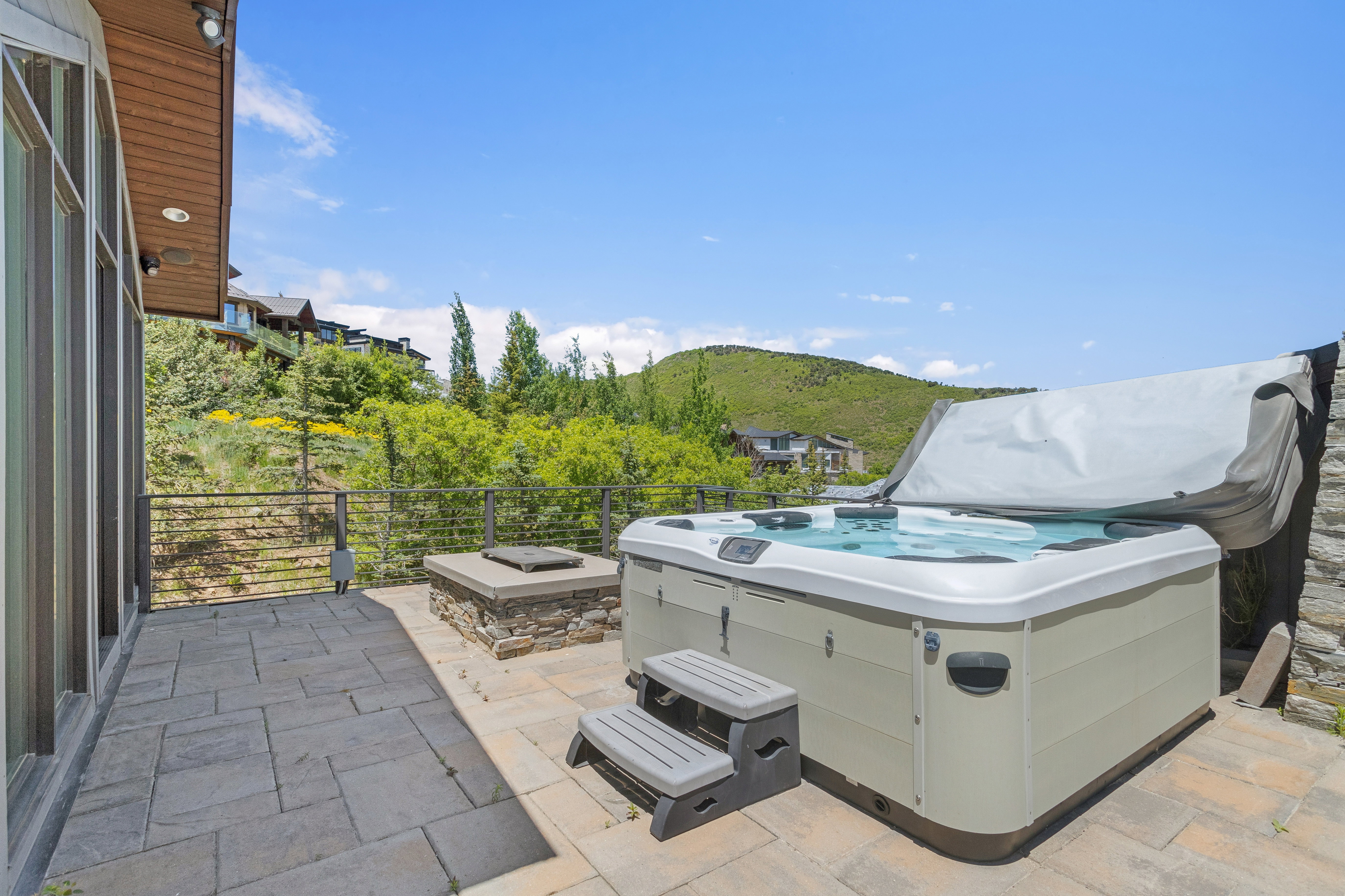 Outdoor patio featuring a hot tub, stone-clad fire pit, and paver flooring