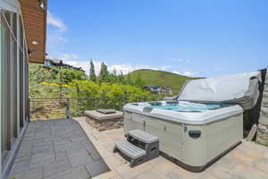 Outdoor patio featuring a hot tub, stone-clad fire pit, and paver flooring