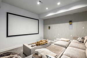 Dedicated media room featuring a large projection screen, recessed lighting, wall-mounted speakers, and a textured accent wall