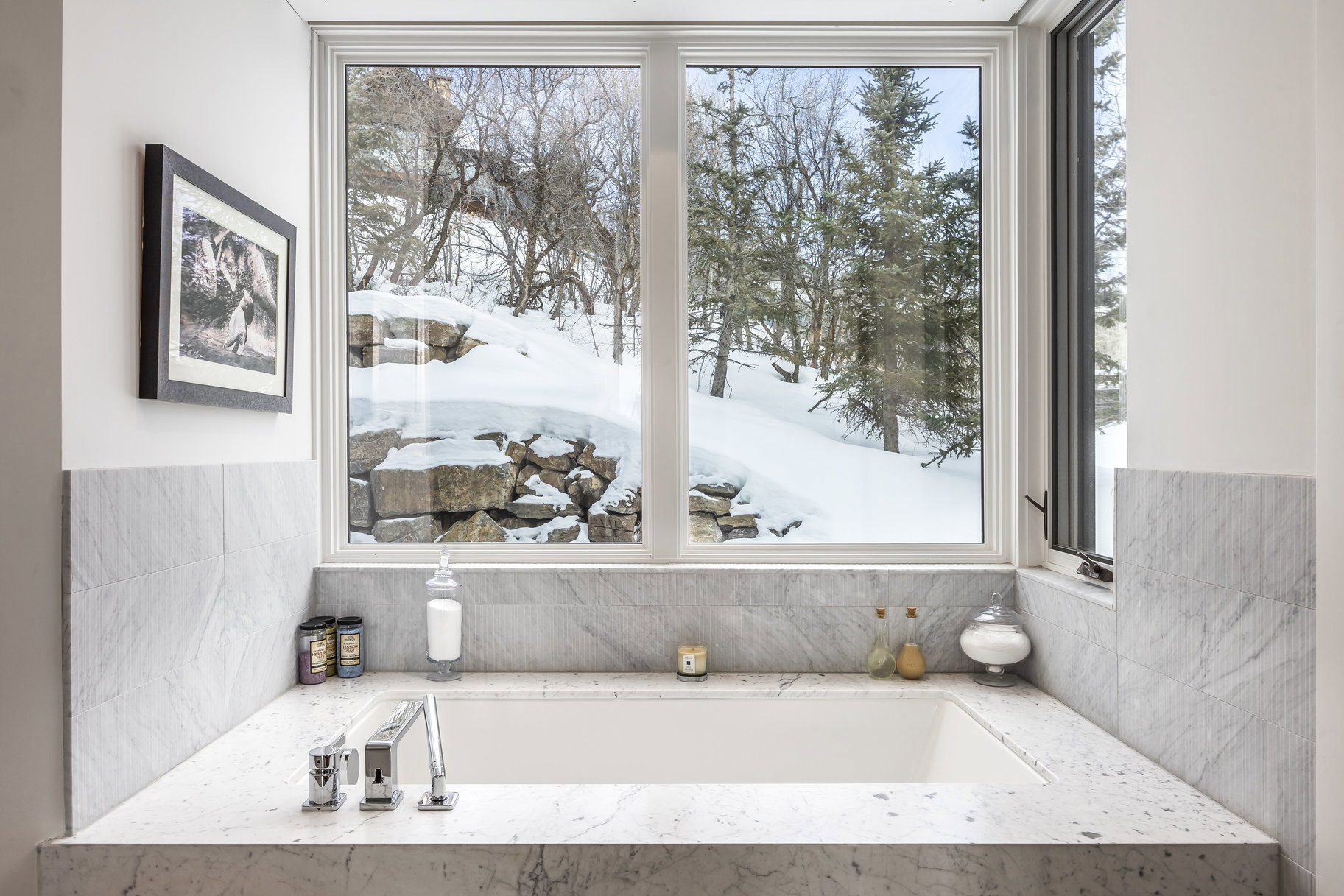 Built-in soaking tub with a deck-mounted faucet and surrounding stone countertop