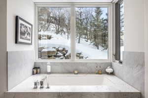 Built-in soaking tub with a deck-mounted faucet and surrounding stone countertop