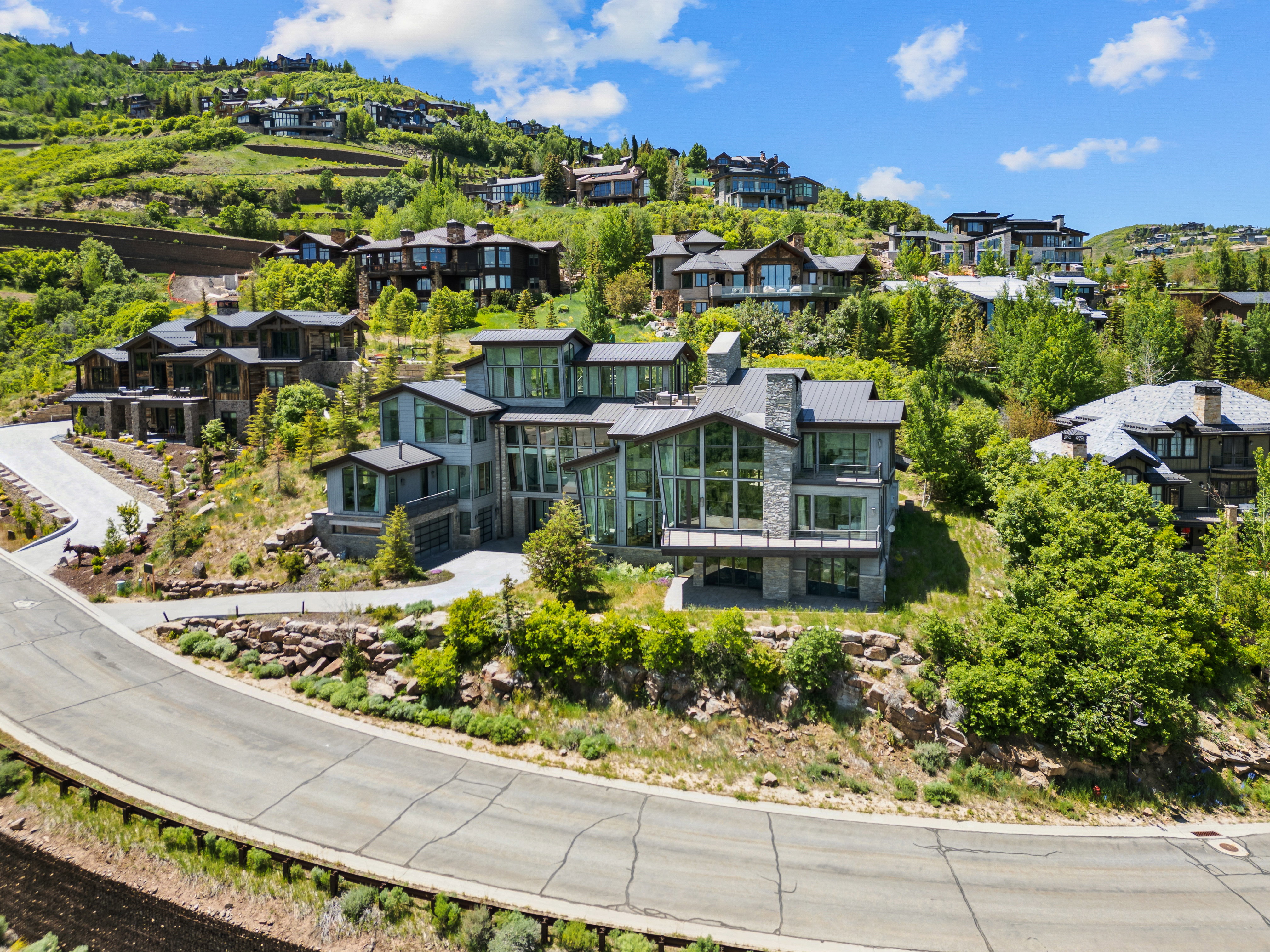 Modern multi-level home with extensive glazing, stone accents, and a metal roof