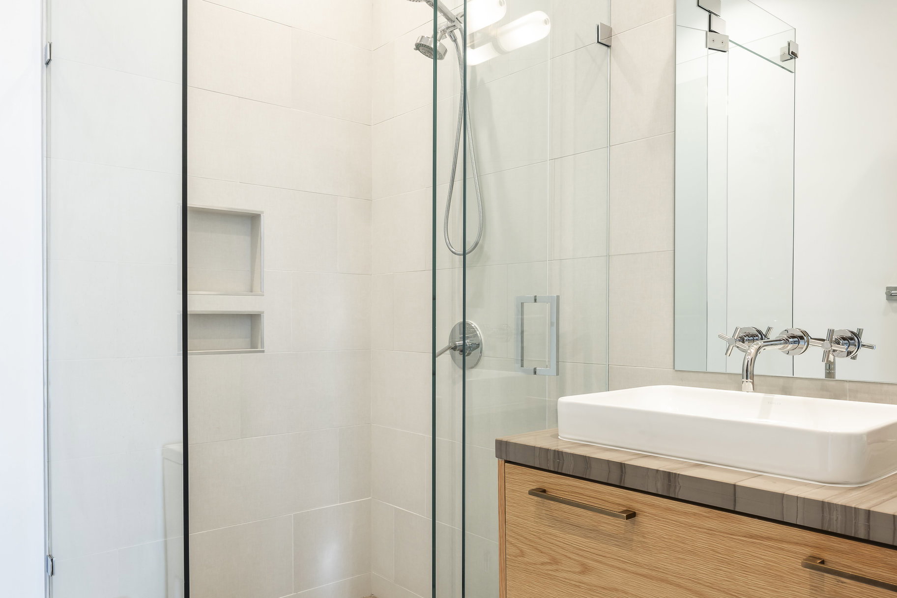 Modern bathroom featuring a walk-in shower with light-toned tile, a built-in shower niche, and a glass enclosure