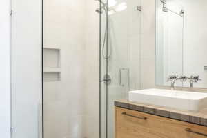 Modern bathroom featuring a walk-in shower with light-toned tile, a built-in shower niche, and a glass enclosure
