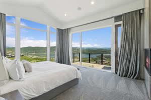 Expansive window wall with mountain and lake scenery, integrated sliding glass door, recessed lighting, and textured carpeting