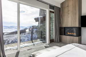 Full-height sliding glass doors opening to an outdoor balcony with metal railings and mountain scenery