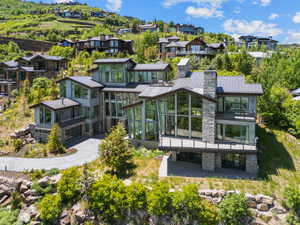 Contemporary multi-level residence featuring expansive windows, stone and siding exterior elements, and multiple balconies
