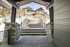 Grand exterior stairway featuring horizontal railings and stone-clad pillars, leading to an upper residence with multiple windows