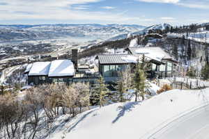 Modern architecture featuring expansive windows, multiple outdoor terrace spaces, a stone chimney, and a metal roof