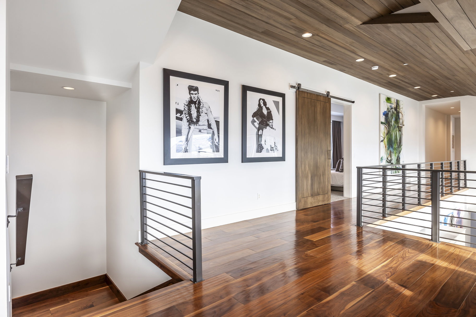 Hardwood flooring throughout a bright hallway featuring a wood-panel ceiling with recessed lighting