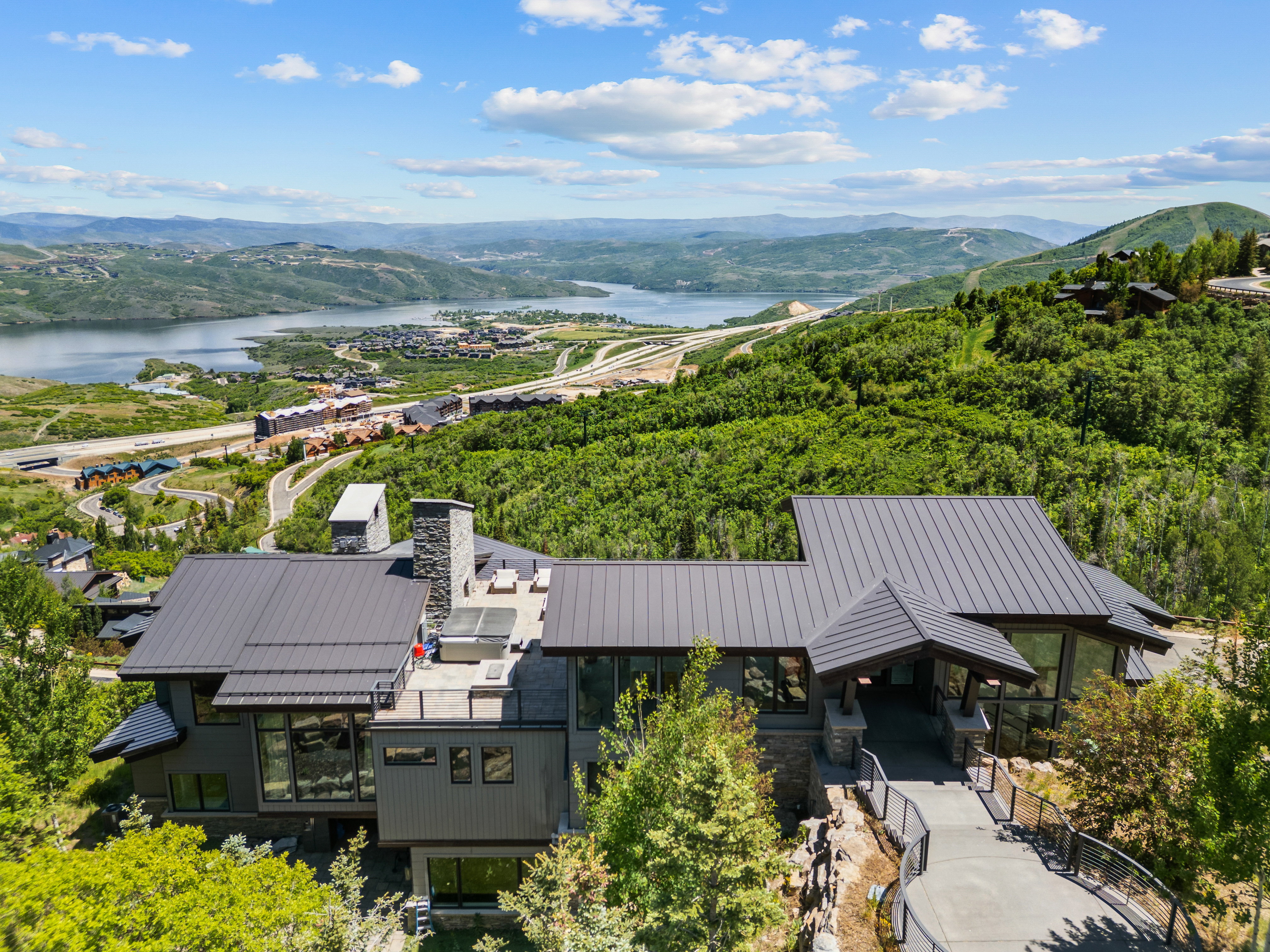 Modern mountain residence featuring a multi-level design, a metal standing seam roof, and a stone chimney