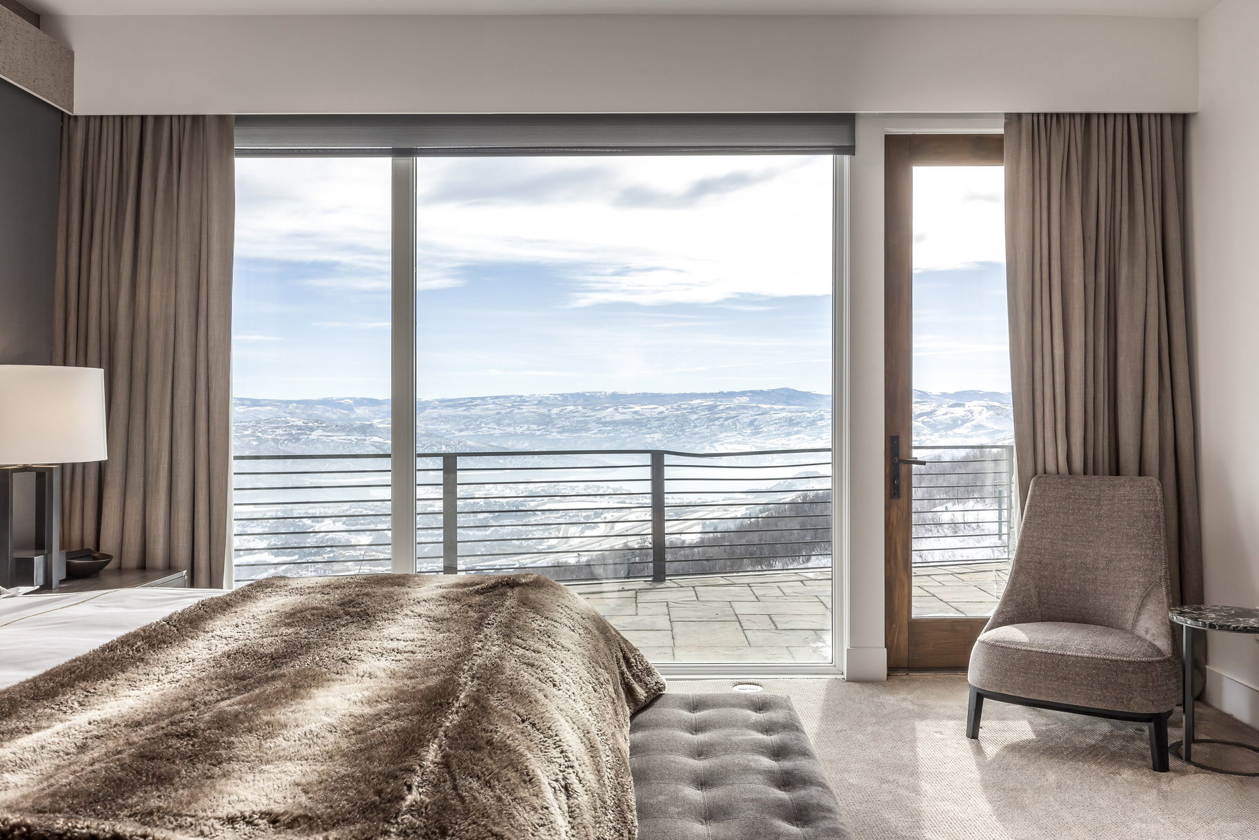 Floor-to-ceiling sliding glass doors open to an outdoor patio with a metal railing