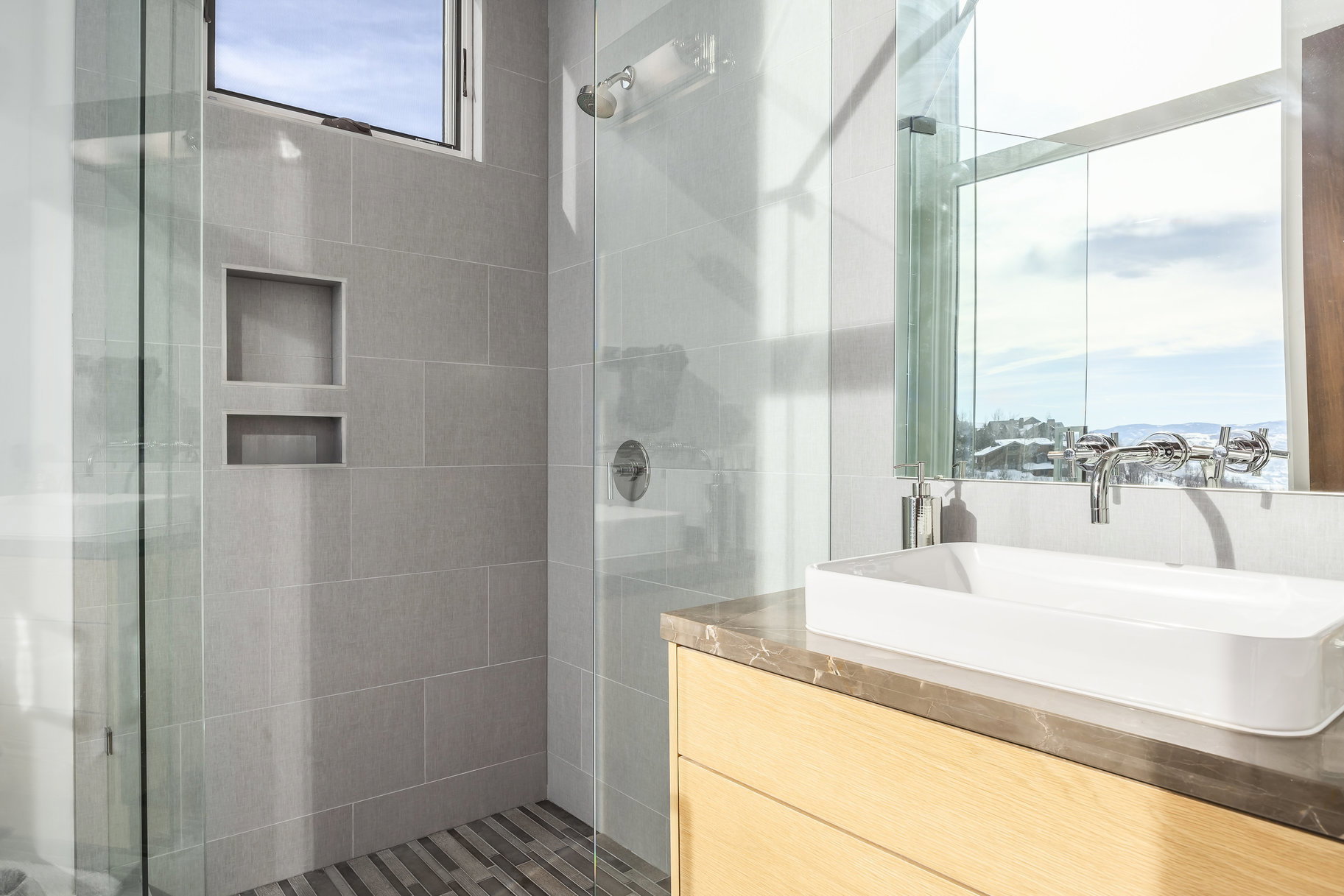 Bathroom featuring a glass-enclosed shower, large format tile walls, and integrated shower niches