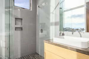 Bathroom featuring a glass-enclosed shower, large format tile walls, and integrated shower niches