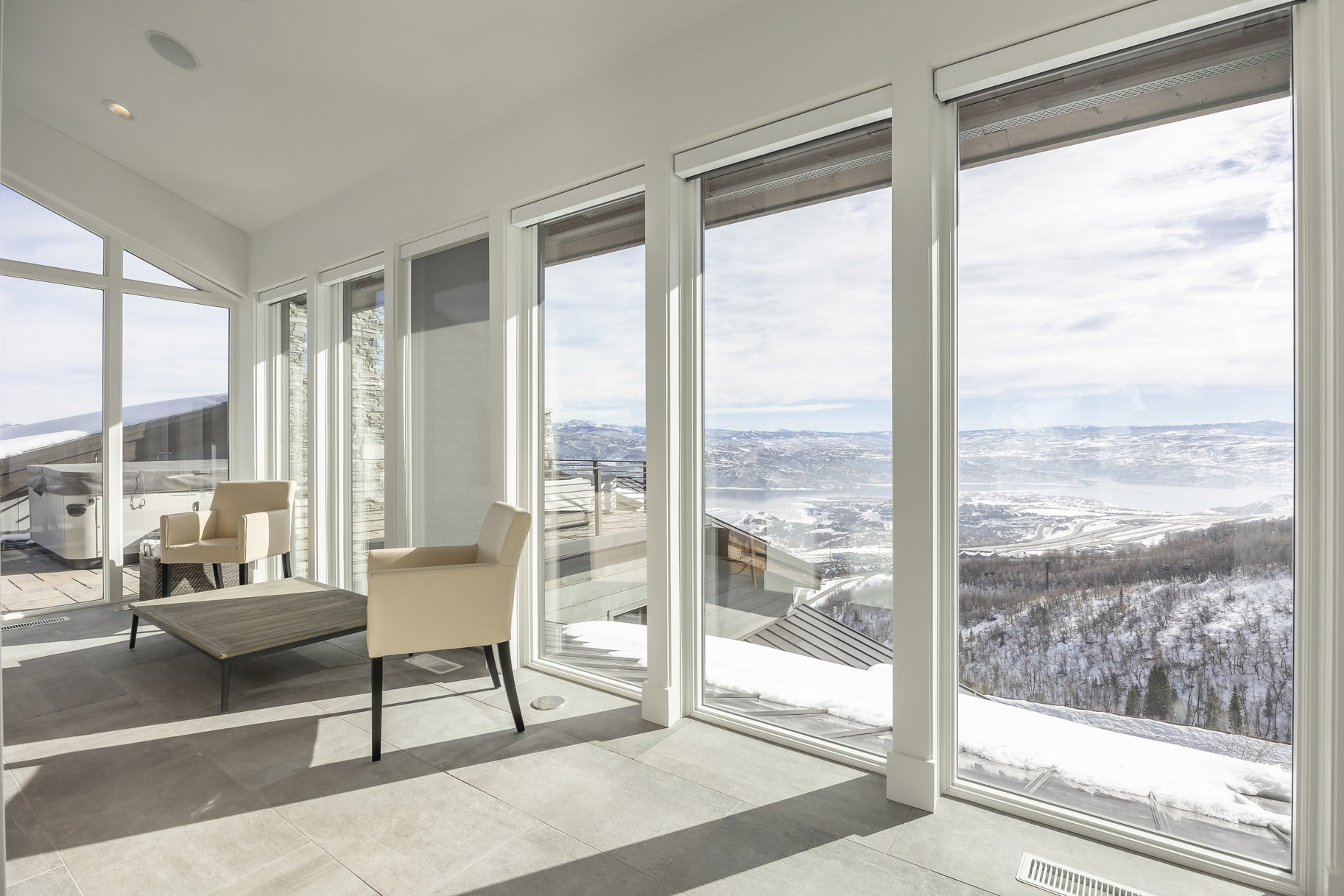 Floor-to-ceiling windows with expansive scenery, showcasing a large patio area with a built-in hot tub