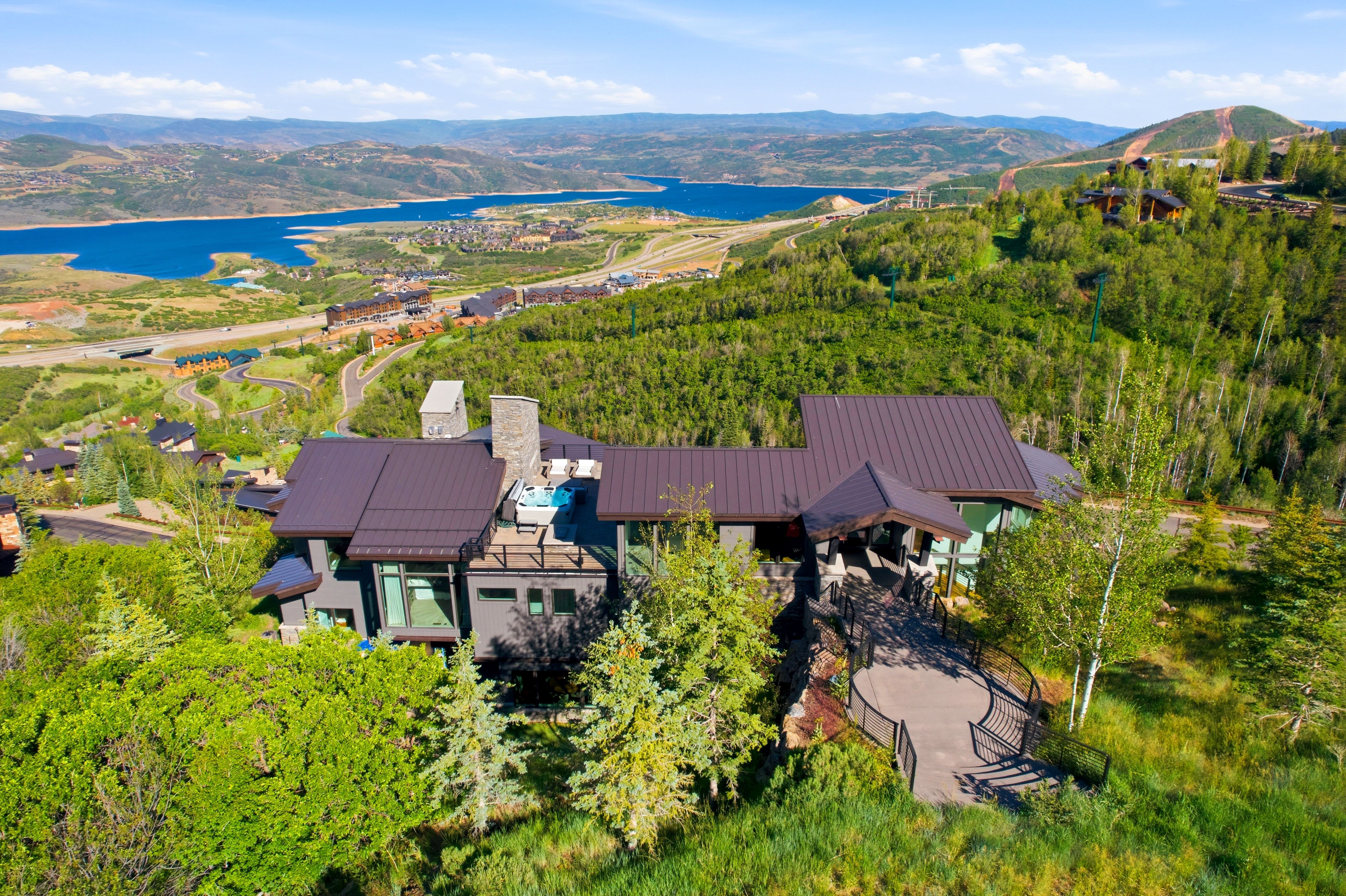 Contemporary residence featuring a brown metal roof, stone chimney, and expansive windows
