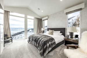 Carpeted bedroom with a vaulted ceiling, floor-to-ceiling windows, and integrated recessed lighting