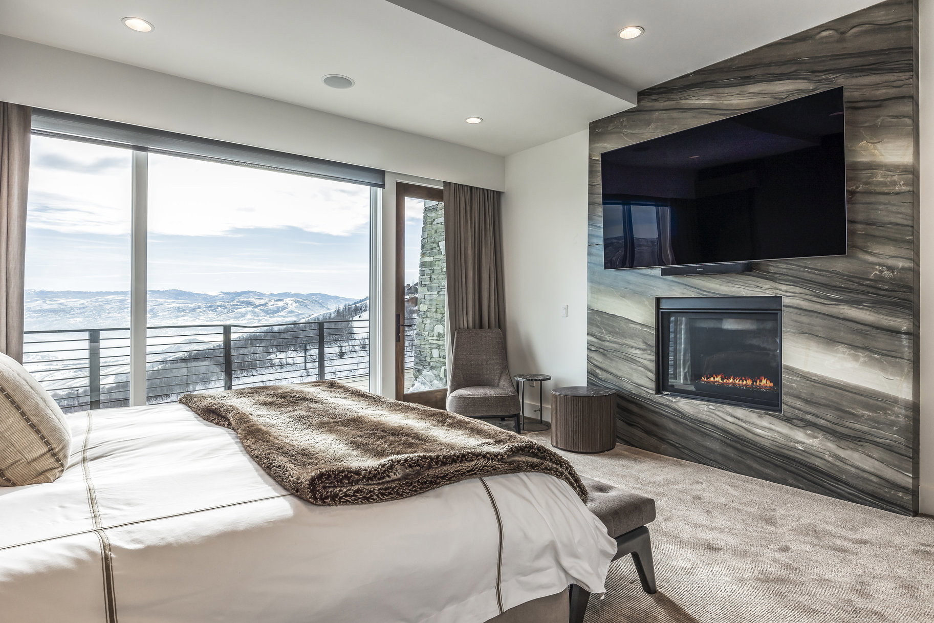 Spacious bedroom with expansive window walls framing a snowy mountain backdrop