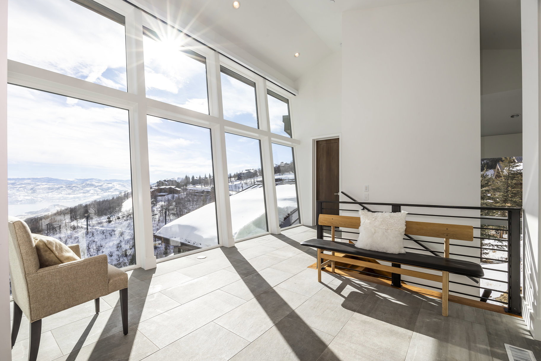 Floor-to-ceiling windows with expansive mountain scenery, vaulted ceilings, recessed lighting, light-toned flooring, and a contemporary railing system