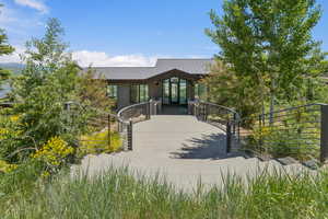 Contemporary exterior featuring a metal roof, expansive windows, and a curved concrete entryway with modern cable railings
