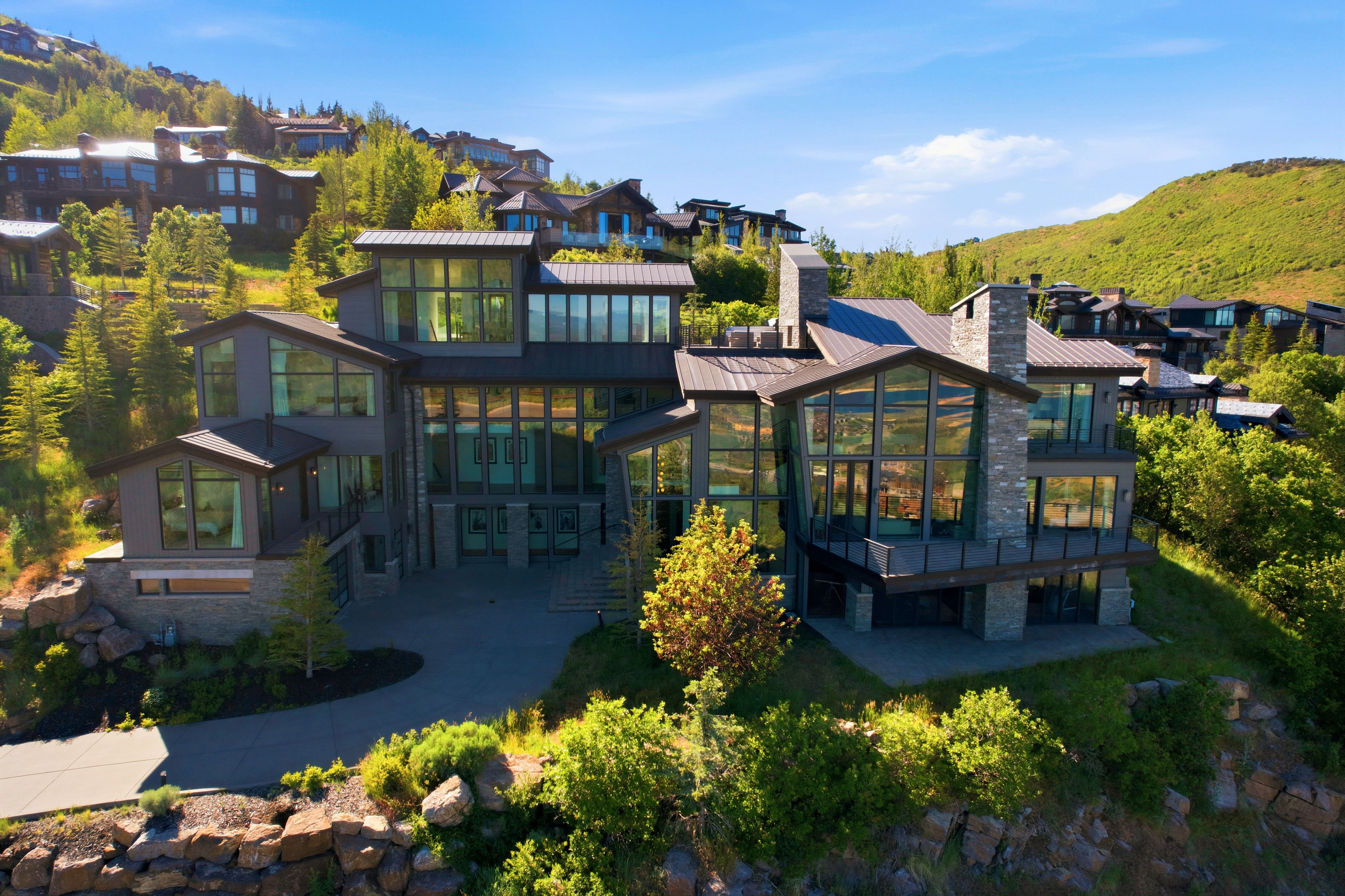 Multi-level contemporary residence featuring extensive window walls, stone accents, and multiple balconies
