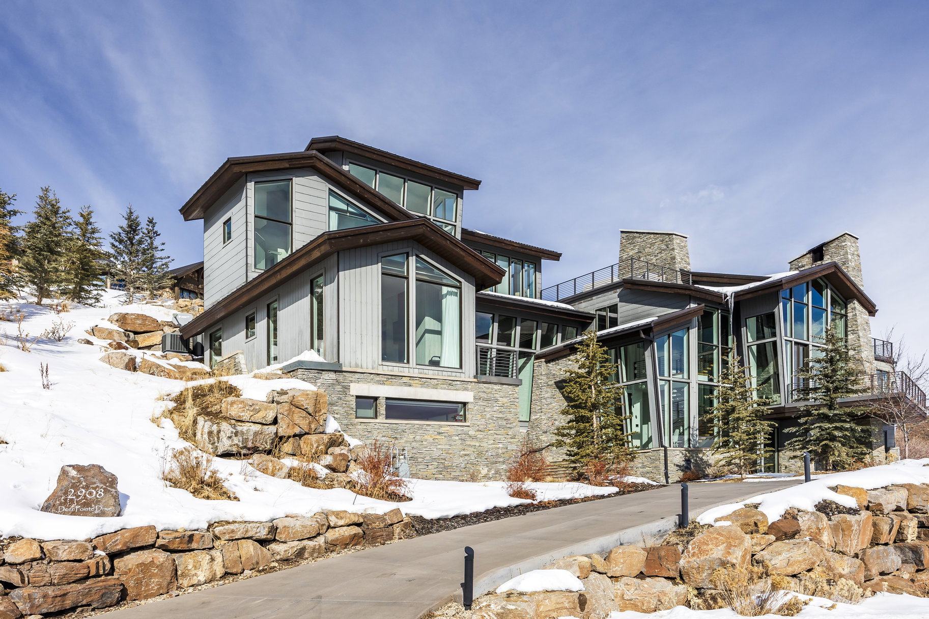 Contemporary multi-level residence featuring extensive stone cladding and gray siding