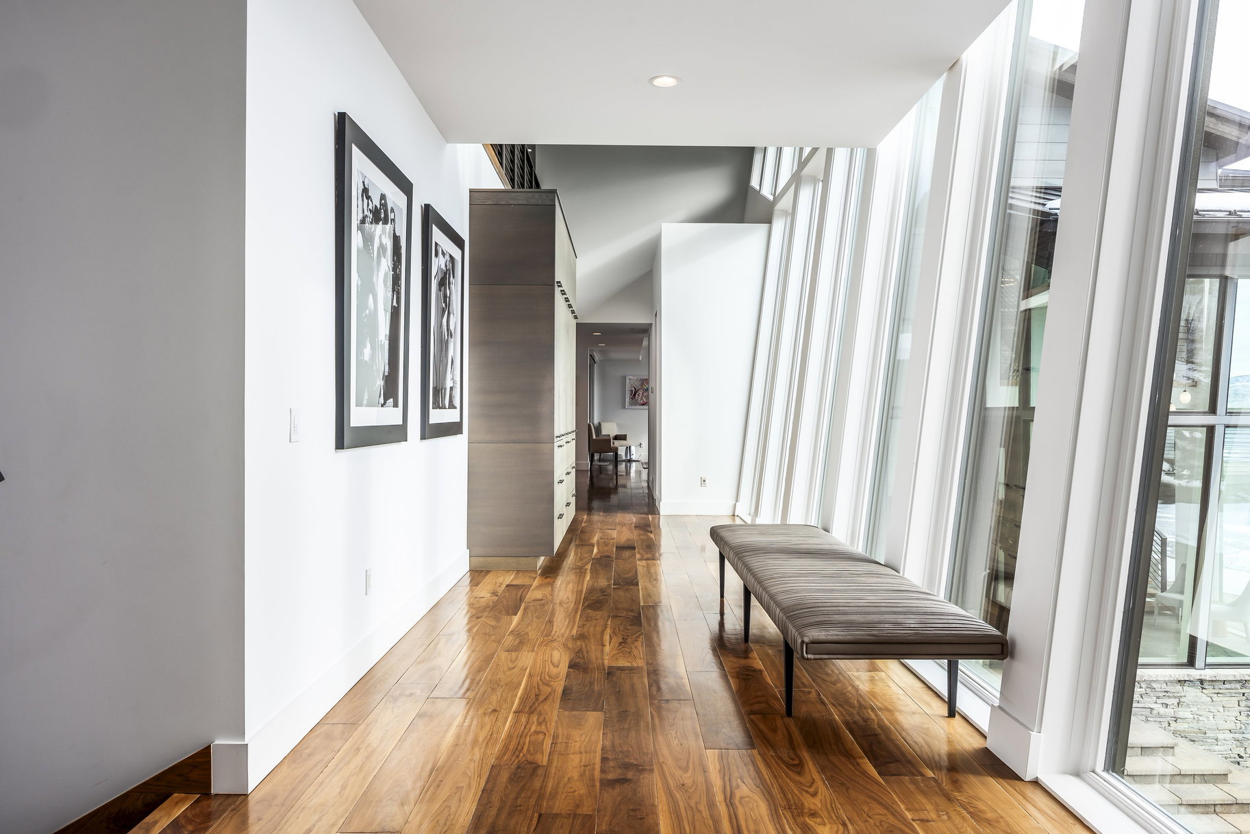Hallway featuring a wall of floor-to-ceiling windows, wood-finish flooring, and integrated wall cabinetry