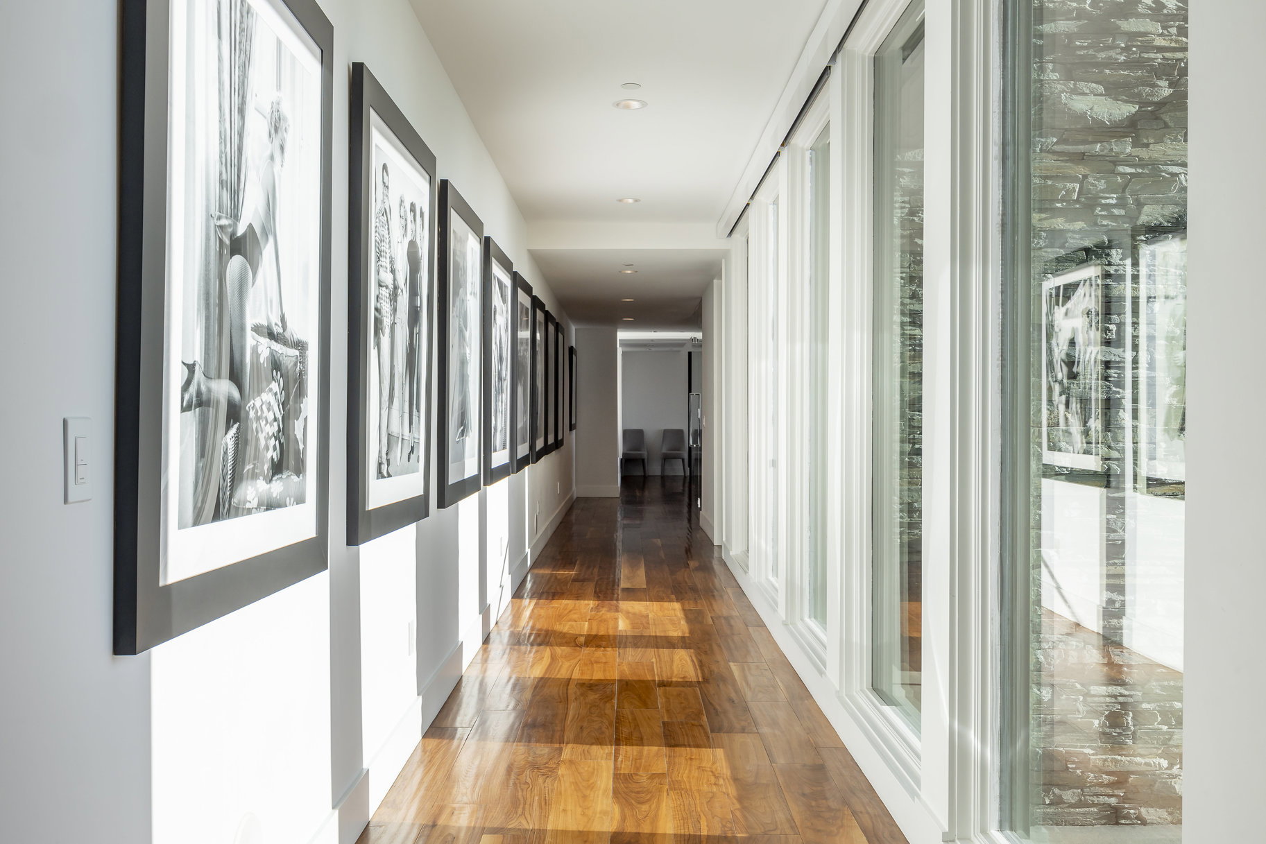 Long hallway featuring wood-finish flooring, recessed lighting, and a wall of floor-to-ceiling windows
