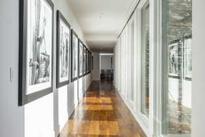 Long hallway featuring wood-finish flooring, recessed lighting, and a wall of floor-to-ceiling windows