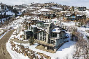 Contemporary mountain residence featuring multiple levels, extensive glazing, a stone chimney, and balconies