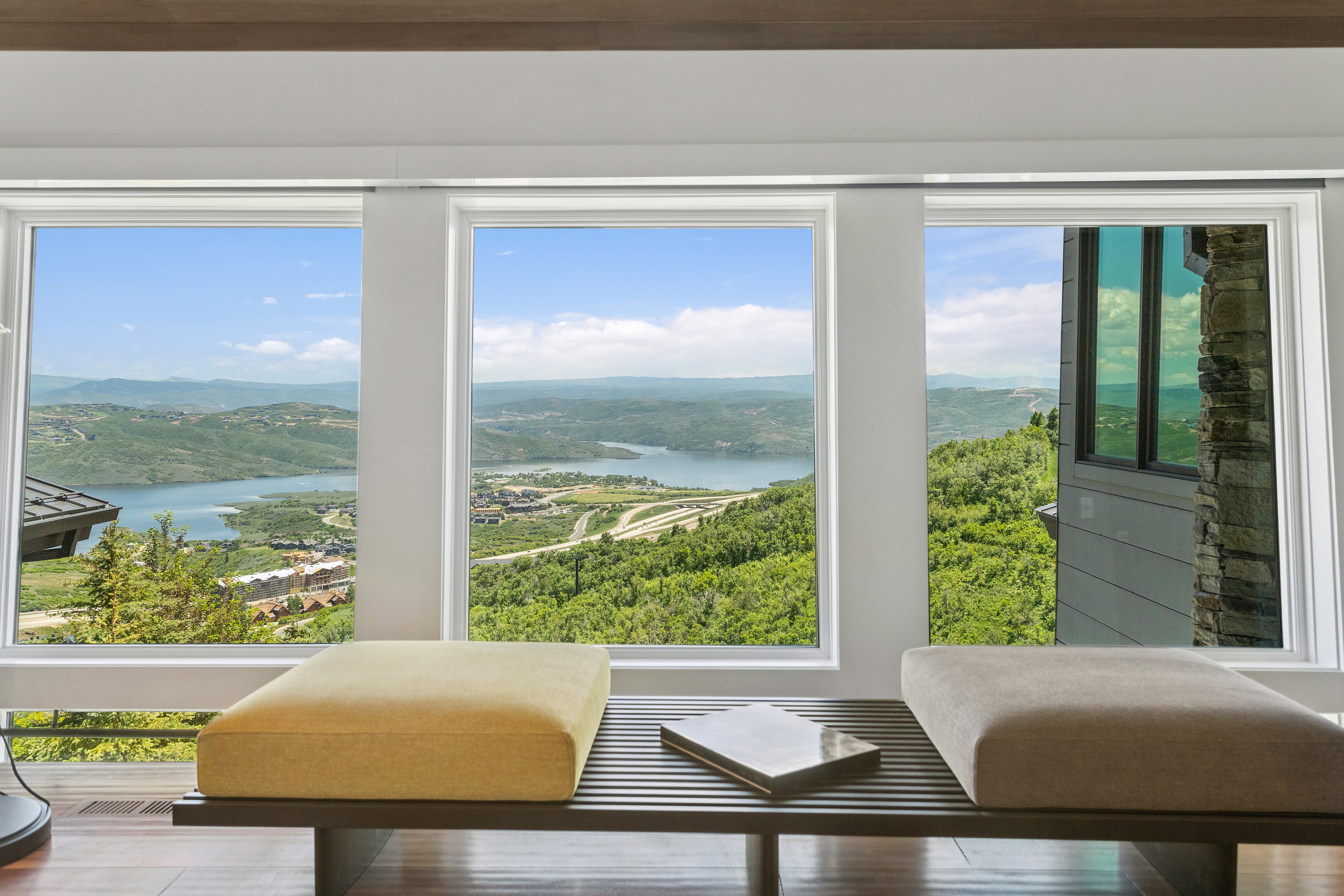 Panoramic windows framing a serene lake and verdant mountainous landscape