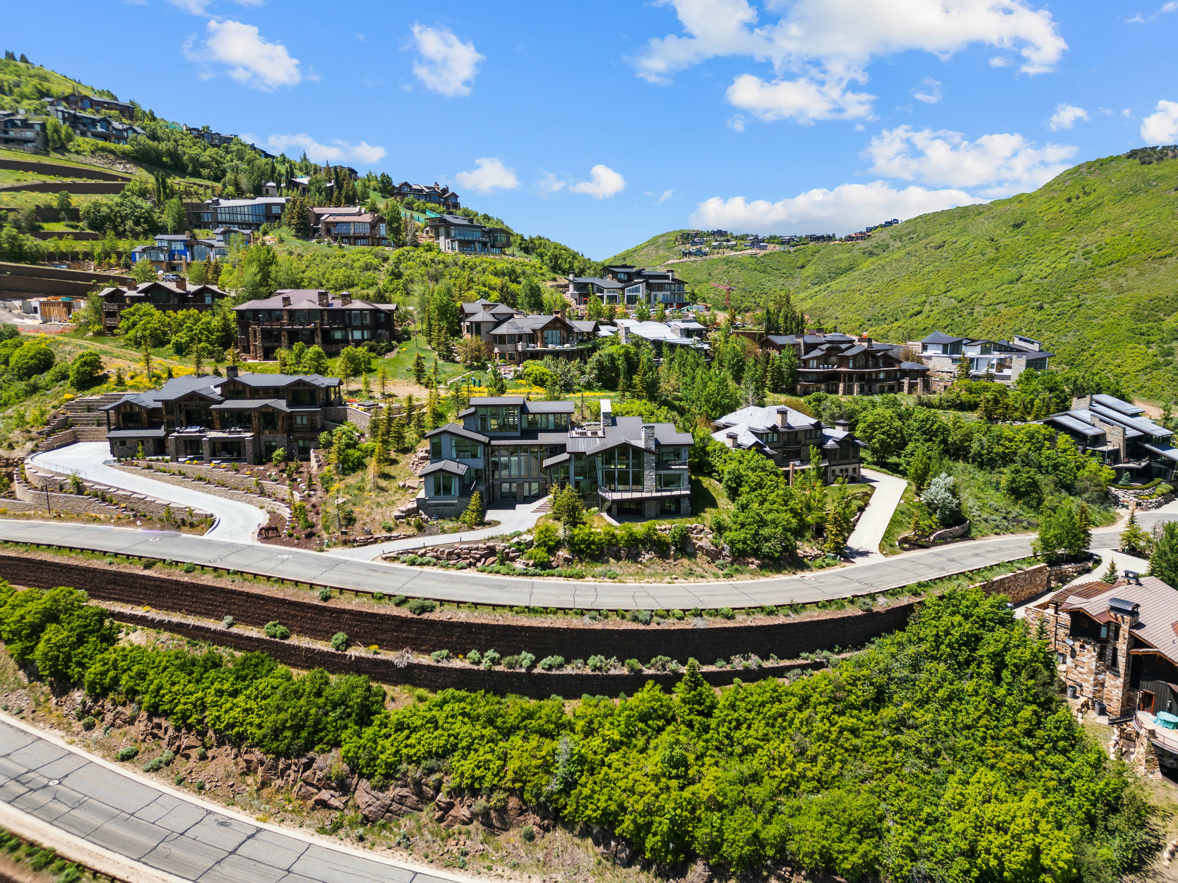 Expansive hillside community featuring multiple residences with varied architectural styles, terraced landscaping, and paved roadways