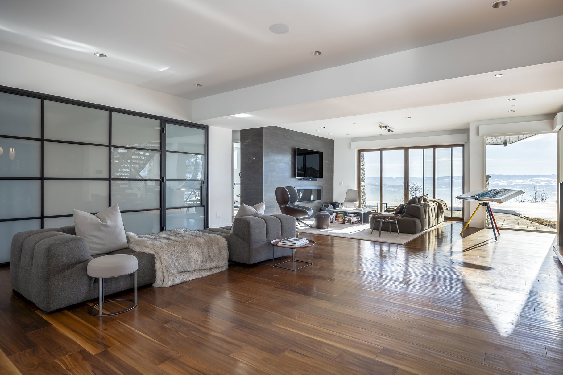 Spacious interior featuring wood-finish flooring, recessed lighting, and a full wall of bi-fold glass doors