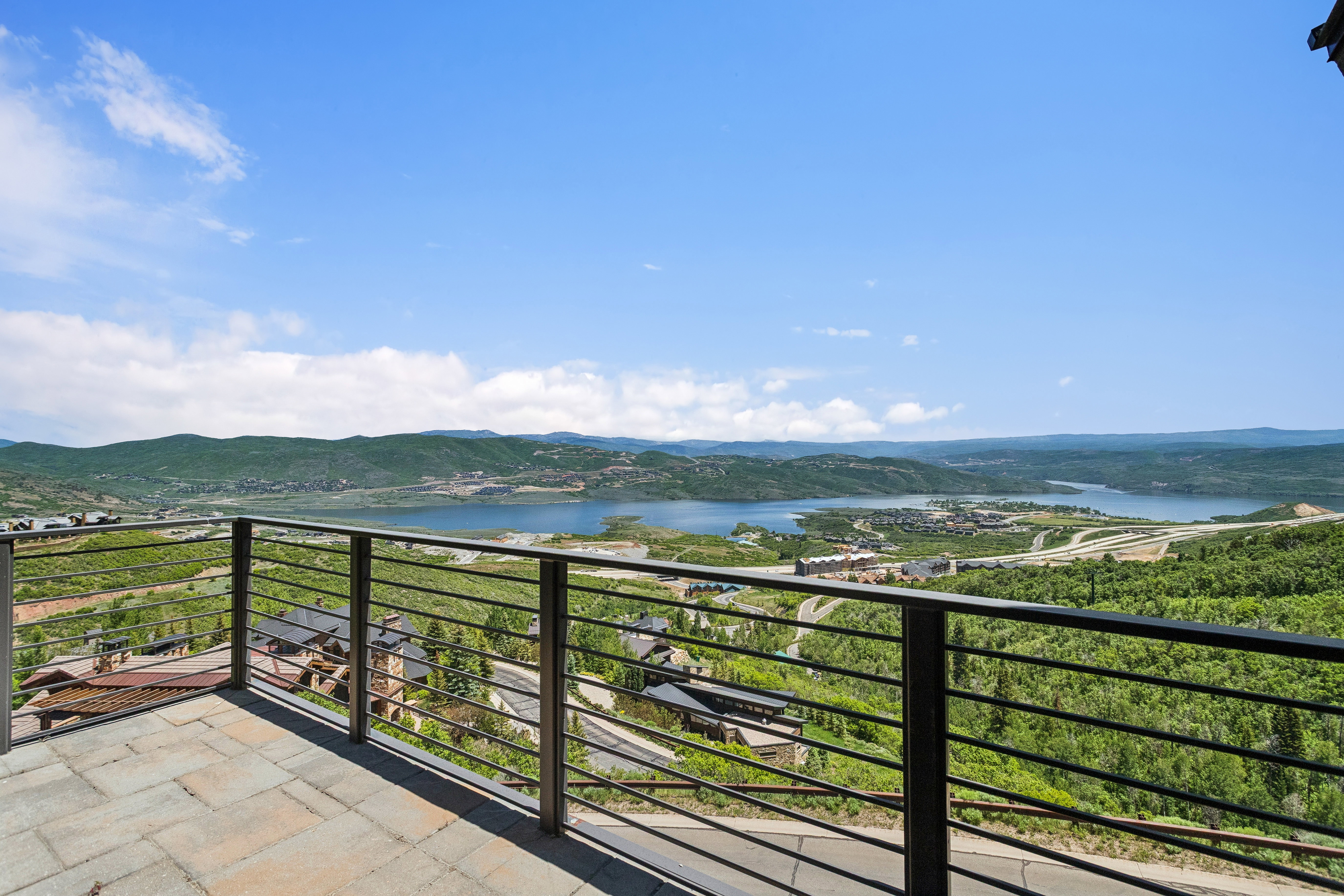 Outdoor patio featuring a paver surface, cable railing, and expansive mountain and lake scenery