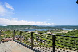 Outdoor patio featuring a paver surface, cable railing, and expansive mountain and lake scenery